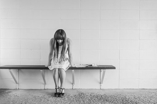 grayscale photography of woman sitting on a bench
